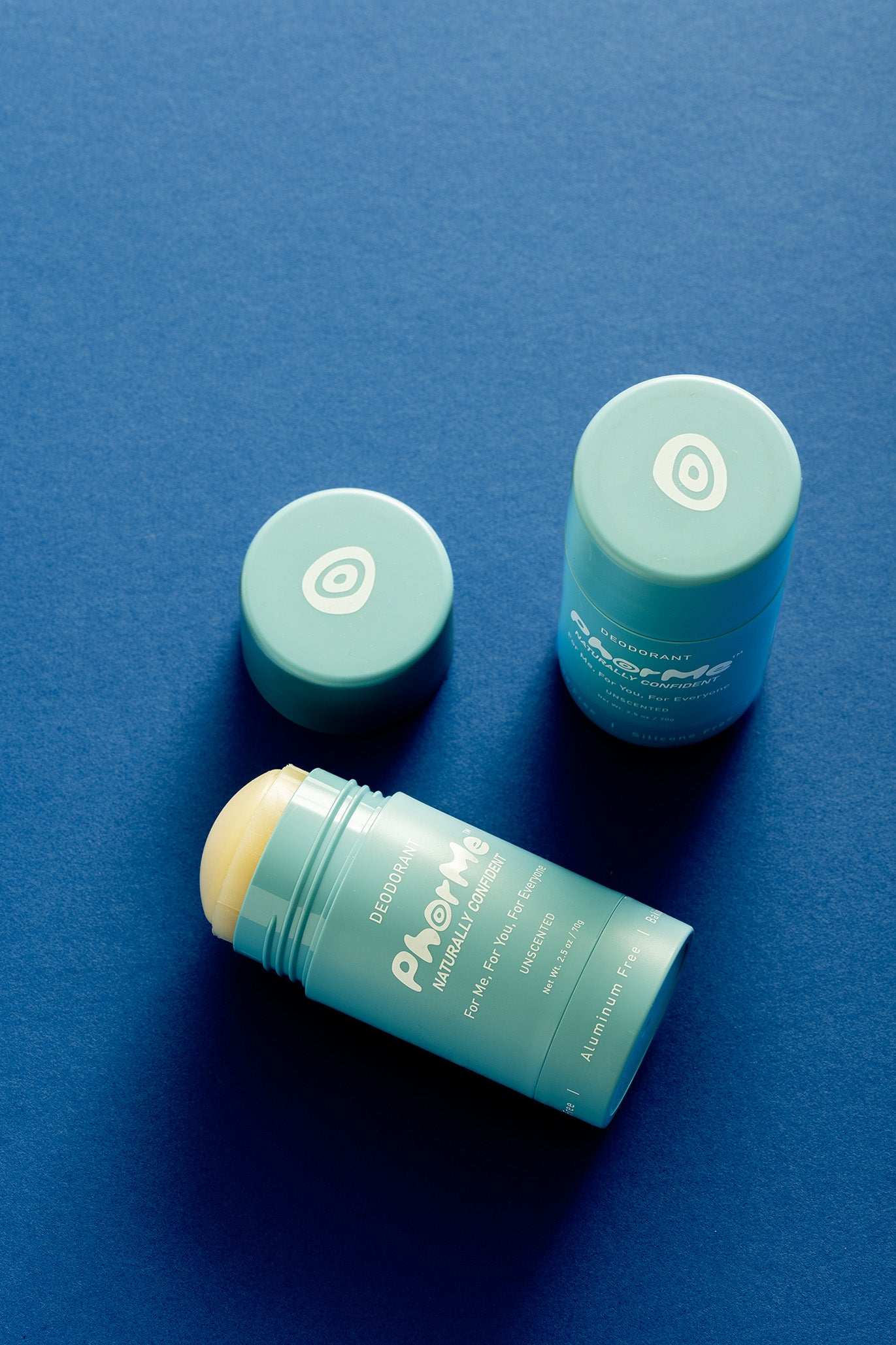 PhorMe unscented natural deodorant sticks with teal caps featuring the brand’s evil eye symbol, arranged on a deep blue background. Aluminum-free, baking soda-free deodorant designed for sensitive skin and everyday use.