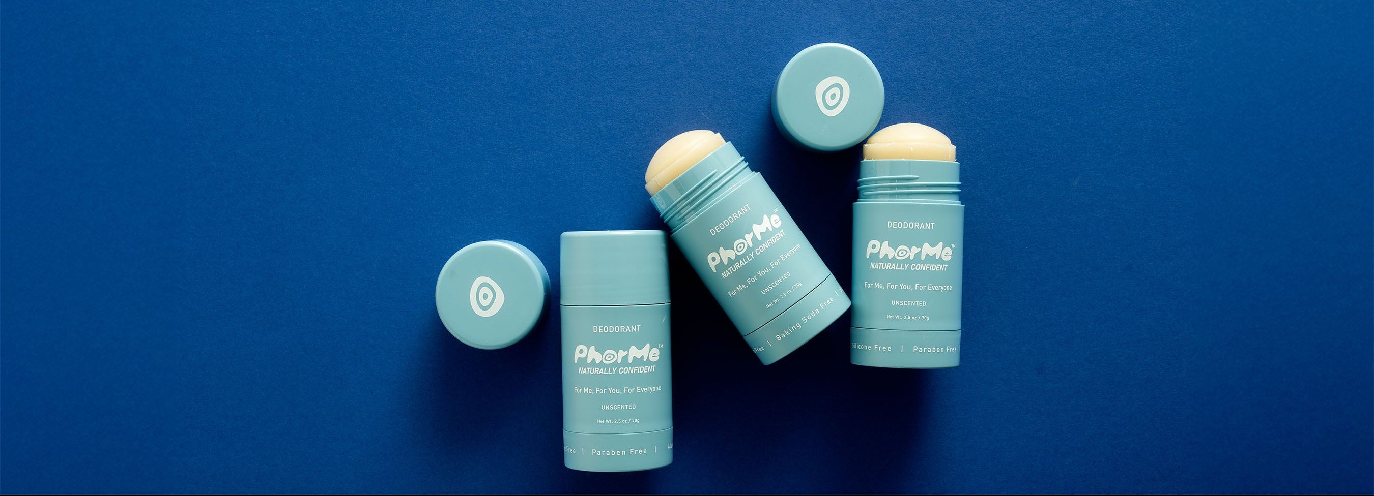 Three PhorMe unscented natural deodorant sticks with teal packaging and open caps showing the solid balm, displayed on a deep blue background. Aluminum-free, paraben-free deodorant designed for every body.